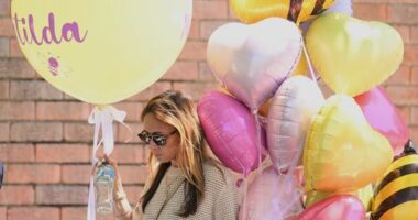 A woman carries balloons to the funeral of Bondi Beach mass shooting victim 10-year-old Matilda, whose last name is being withheld at the request of her family, in Sydney, Thursday, Dec. 18, 2025. (AP Photo/Steve Markham)