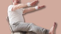 Elderly man practicing yoga asana or sport exercise for legs and hands on chair