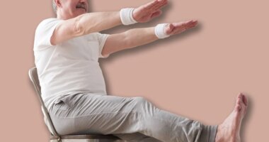 Elderly man practicing yoga asana or sport exercise for legs and hands on chair