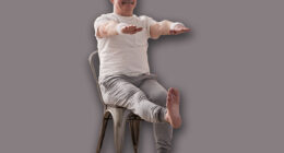 Elderly man practicing yoga asana or sport exercise for legs and hands on chair