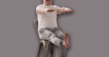 Elderly man practicing yoga asana or sport exercise for legs and hands on chair