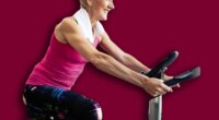 Happy fit mature woman and man cycling on exercise bikes to stay healthy