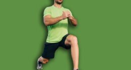 Full body handsome mature ethnic male in summer sportswear doing forward lunge on left leg with hands together while doing workout against contemporary geometric building