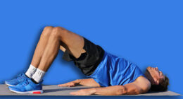 Fitness man doing bodyweight glute floor bridge pose yoga exercise. Fit athlete exercising glutes muscles with butt raise at summer outdoor gym instruction class on grass.