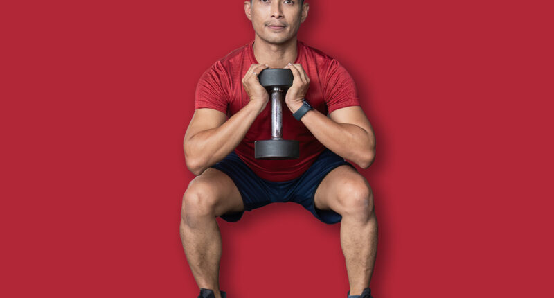 Wellness through Strength Training. Man performing squat with dumbbell in gym.