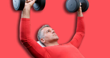 Mature man lifting dumbells at fitness gym