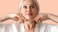 Mature woman doing face building exercise on light background