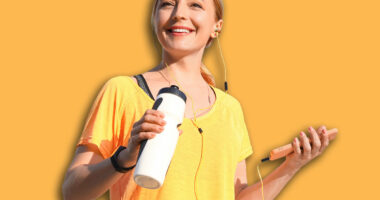 Sporty mature woman with bottle of water listening to music outdoors