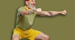 Full size body length fitness vivid elderly gray-haired bearded man 40s years old in headband khaki t-shirt look aside doing side squat isolated on plain pastel light purple background studio portrait
