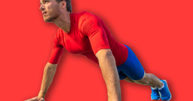 Fit man doing push ups exercise at outdoor gym. Core body workout athlete planking or doing pushup on grass.