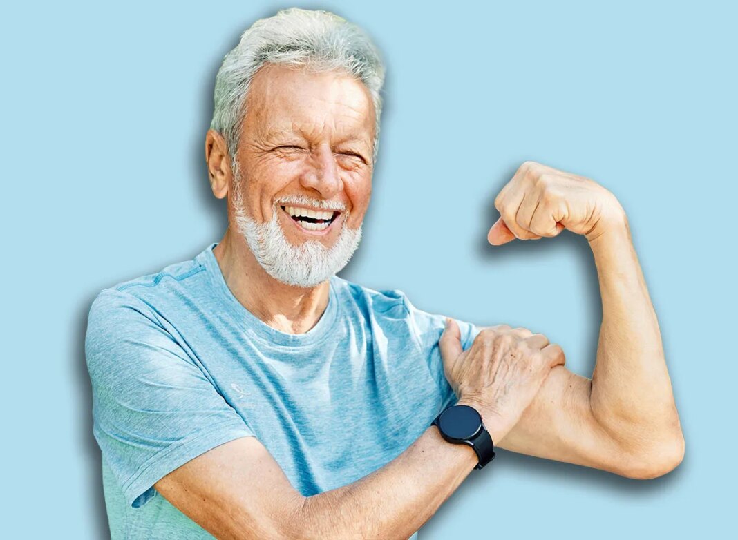 Portrait of a happy positive old senior man showing biceps and power standing outdoors in park or nature, healthy lifestyle, active senior, vitality and humor concepts