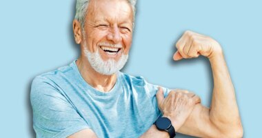 Portrait of a happy positive old senior man showing biceps and power standing outdoors in park or nature, healthy lifestyle, active senior, vitality and humor concepts