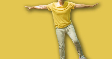 Balancing exercise outdoors. Mature woman standing on one leg, exercising balance