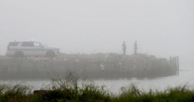 Galveston Police officers watch the water on Galveston Bay west of the Galveston causeway, Monday, Dec. 22, 2025, near Galveston, Texas, as emergency personnel search for a small airplane that went down in the bay in heavy fog. (Jennifer Reynolds/The Galveston County Daily News via AP)
