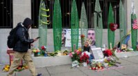 A person walks past a makeshift memorial for U.S. Army Spc. Sarah Beckstrom and U.S. Air Force Staff Sgt. Andrew Wolfe outside of Farragut West Station, near the site where the two National Guard members were shot, Monday, Dec. 1, 2025, in Washington. (AP Photo/Julia Demaree Nikhinson)
