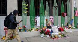 A person walks past a makeshift memorial for U.S. Army Spc. Sarah Beckstrom and U.S. Air Force Staff Sgt. Andrew Wolfe outside of Farragut West Station, near the site where the two National Guard members were shot, Monday, Dec. 1, 2025, in Washington. (AP Photo/Julia Demaree Nikhinson)