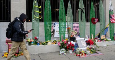 A person walks past a makeshift memorial for U.S. Army Spc. Sarah Beckstrom and U.S. Air Force Staff Sgt. Andrew Wolfe outside of Farragut West Station, near the site where the two National Guard members were shot, Monday, Dec. 1, 2025, in Washington. (AP Photo/Julia Demaree Nikhinson)