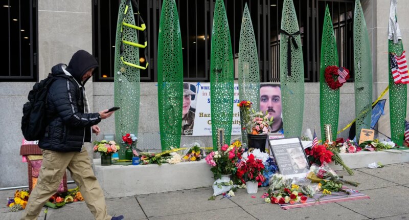 A person walks past a makeshift memorial for U.S. Army Spc. Sarah Beckstrom and U.S. Air Force Staff Sgt. Andrew Wolfe outside of Farragut West Station, near the site where the two National Guard members were shot, Monday, Dec. 1, 2025, in Washington. (AP Photo/Julia Demaree Nikhinson)