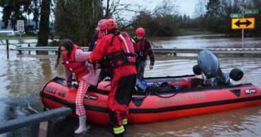 Maery Schine, 11, is helped out of a rescue boat by rescue workers with Chehalis Fire after evacuating with her father Patric, second from left, following flooding after heavy rains in the region Tuesday, Dec. 9, 2025, in Chehalis, Wash. (AP Photo/Lindsey Wasson)