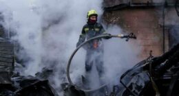 A rescue worker puts out a fire of a house destroyed after a Russian strike on Kyiv, Ukraine, on Saturday, Dec. 27, 2025. (AP Photo/Evgeniy Maloletka)