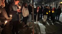 A crowd of people holding candles gather outside the home of Massachusetts Institute of Technology professor Nuno F.G. Loureiro in Brookline, Mass., Tuesday, Dec. 16, 2025. (AP Photo/Leah Willingham)