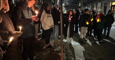 A crowd of people holding candles gather outside the home of Massachusetts Institute of Technology professor Nuno F.G. Loureiro in Brookline, Mass., Tuesday, Dec. 16, 2025. (AP Photo/Leah Willingham)