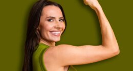 Confident young woman smiling and flexing her arm against a bright yellow background, symbolizing strength, positivity, and cheerful energy.