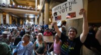 FILE - Annette Groos holds a sign before the start of a rally featuring former Transportation Secretary Pete Buttigieg at the Statehouse in Indianapolis, Thursday, Sept. 18, 2025 for Indiana Democrats amid pressure from President Donald Trump on Republicans who control the state