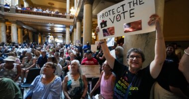 FILE - Annette Groos holds a sign before the start of a rally featuring former Transportation Secretary Pete Buttigieg at the Statehouse in Indianapolis, Thursday, Sept. 18, 2025 for Indiana Democrats amid pressure from President Donald Trump on Republicans who control the state