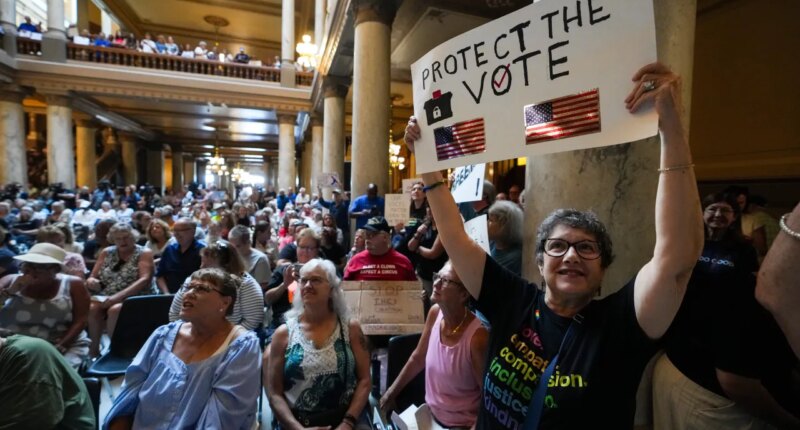 FILE - Annette Groos holds a sign before the start of a rally featuring former Transportation Secretary Pete Buttigieg at the Statehouse in Indianapolis, Thursday, Sept. 18, 2025 for Indiana Democrats amid pressure from President Donald Trump on Republicans who control the state
