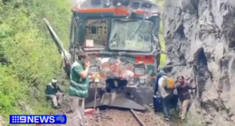 Videos on local media showed train cars with broken windows and dented sides stuck along a rail line hemmed in between a lush forest and a massive rock.