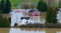 A n aerial view of a home and a barn surrounded by floodwaters in Snohomish, Wash., Thursday, Dec. 11, 2025. (AP Photo/Stephen Brashear)