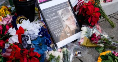 Flowers, challenge coins and other items lay near a photograph of U.S. Army Spc. Sarah Beckstrom at a makeshift memorial outside of Farragut West Station, near the site where two National Guard members were shot, Monday, Dec. 1, 2025, in Washington. (AP Photo/Julia Demaree Nikhinson)
