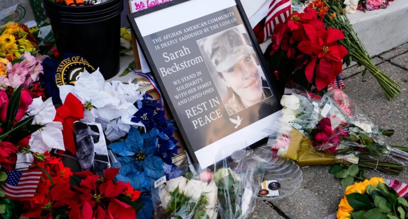 Flowers, challenge coins and other items lay near a photograph of U.S. Army Spc. Sarah Beckstrom at a makeshift memorial outside of Farragut West Station, near the site where two National Guard members were shot, Monday, Dec. 1, 2025, in Washington. (AP Photo/Julia Demaree Nikhinson)