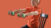 Smiling beautiful senior woman health instructor doing chair exercises with dumbbells