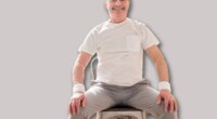 Elderly man wearing sport clothing sitting on chair ready for online yoga lesson