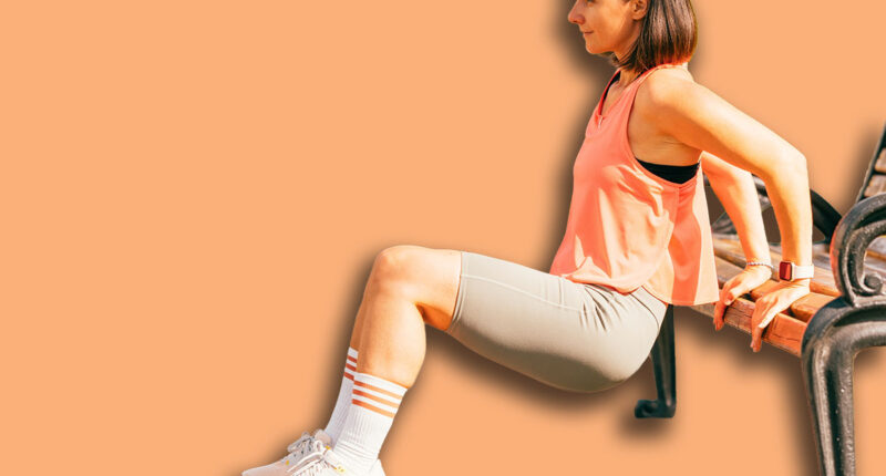 Vertical outdoors shot of a fit woman exercising her triceps on a park bench.