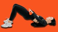 Sporty woman doing glute bridge exercise with orange dumbbells on white background. Concept of fitness, strength training, workout routine, and healthy lifestyle.