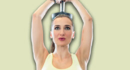 Portrait of a beautiful fit woman with can do attitude exercising triceps extension with dumbbell during workout in a modern fitness club