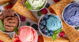 Colorful bright ice cream on bowls, with waffle cones and berries, on white background. Variety of ice cream portions with different flavor with fresh berries top view copy space layout background