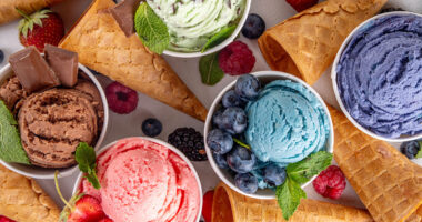 Colorful bright ice cream on bowls, with waffle cones and berries, on white background. Variety of ice cream portions with different flavor with fresh berries top view copy space layout background