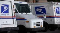 Three USPS mail delivery trucks parked at night.