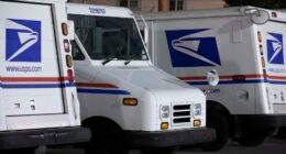 Three USPS mail delivery trucks parked at night.