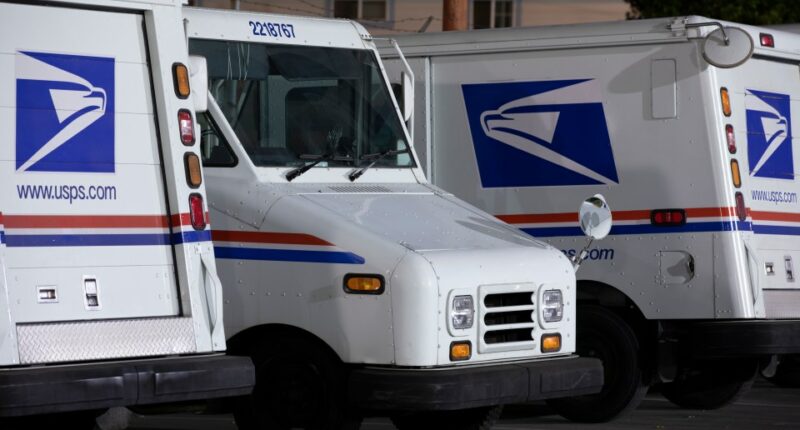 Three USPS mail delivery trucks parked at night.