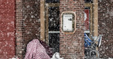 Two people take cover in an entryway of a downtown restaurant on Fourth Avenue, Thursday, Nov. 9, 2023 in Anchorage, Alaska. Four homeless people have died in Anchorage in the last week, underscoring the city’s ongoing struggle to house a large houseless population at the same time winter weather has returned, with more than 2 feet (0.61 meters) of snow falling within 48 hours. (Marc Lester/Anchorage Daily News via AP)
