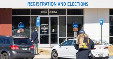 An FBI press office person approaches the Fulton County Election Hub and Operation Center, Wednesday, Jan. 28, 2026, in Union City, Ga. (Arvin Temka/Atlanta Journal-Constitution via AP)