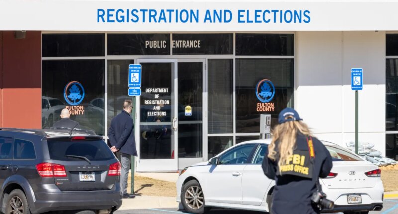 An FBI press office person approaches the Fulton County Election Hub and Operation Center, Wednesday, Jan. 28, 2026, in Union City, Ga. (Arvin Temka/Atlanta Journal-Constitution via AP)