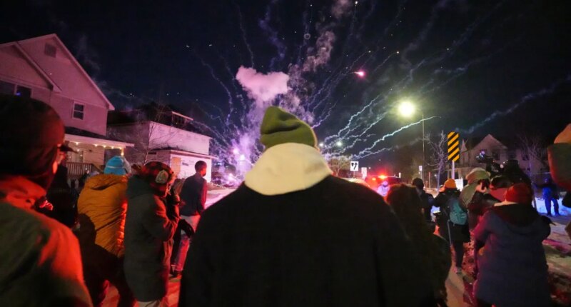 People react after a firework was set off near the scene of a reported shooting Wednesday, Jan. 14, 2026, in Minneapolis. (AP Photo/Abbie Parr)