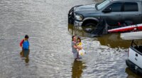 People wade through an rv park flooded by the