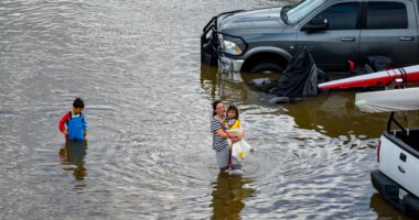 People wade through an rv park flooded by the